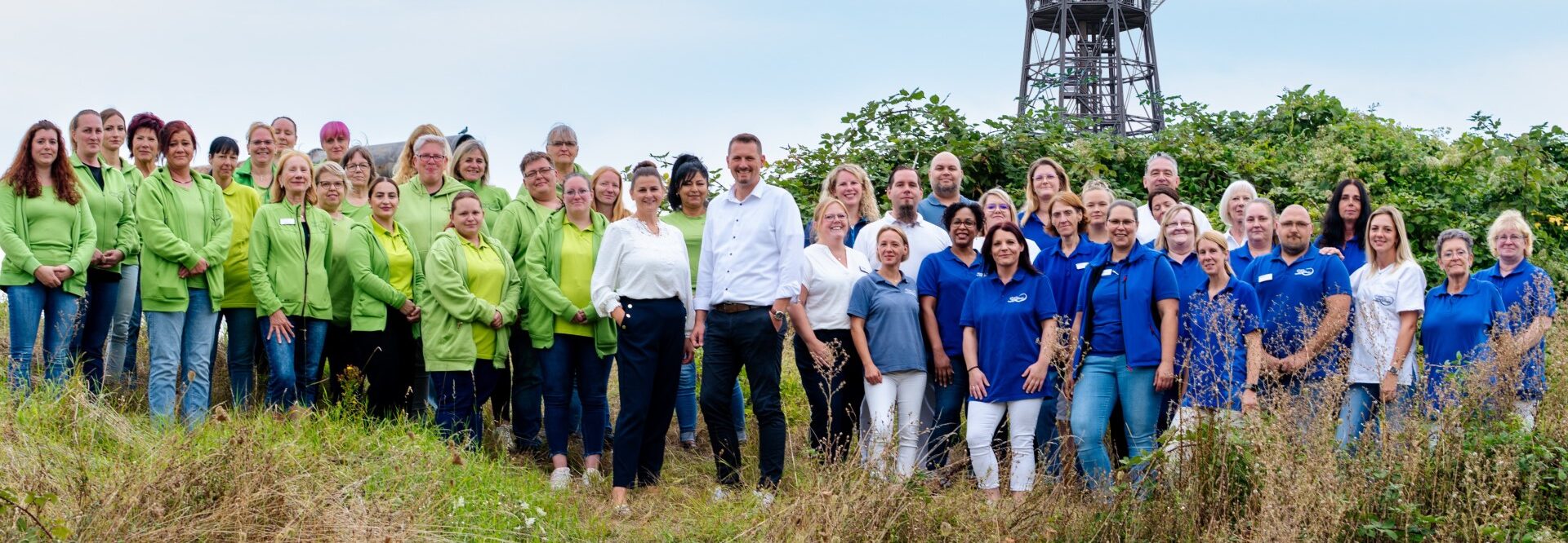 Gesamtteam1920 Die Teams der Gloger Pflege und der Gloger Hausdienste auf einer Wiese vor dem Ilseder Wasserturm